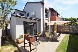 a house with a patio with a table and an umbrella at Elroys in Sandton