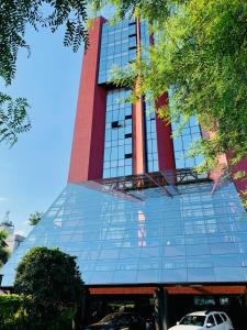 um edifício de vidro alto com carros estacionados em frente em Blue Tree Towers Joinville em Joinville
