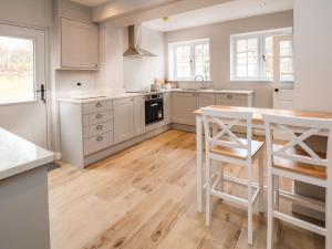 a kitchen with white cabinets and a wooden floor at 2 Golf Links Cottages in Northwich