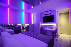 a bedroom with purple and pink lights and a bed at Nuu Motel in São Paulo