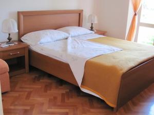a large bed in a bedroom with a wooden floor at Guesthouse Marija in Cavtat