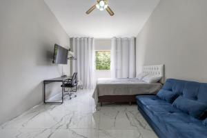 ein Wohnzimmer mit einem blauen Sofa und einem Bett in der Unterkunft Apart Veneza l Garagem l Pet Friendly l Centro de Águas de Lindóia in Águas de Lindóia