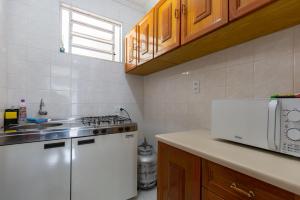 una cucina con frigorifero bianco e forno a microonde di Apart Veneza l Garagem l Pet Friendly l Centro de Águas de Lindóia ad Águas de Lindóia