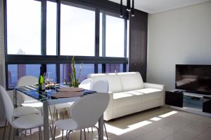 LUXURY Residence Gemelos 26 في بنيدورم: غرفة معيشة مع أريكة بيضاء وطاولة وكراسي