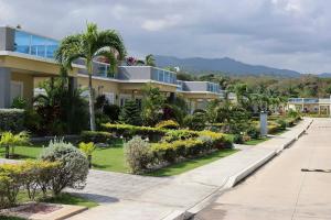 a row of houses with palm trees and bushes at Beach Holidays at Marina Villa in Saint Annʼs Bay