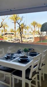 een tafel met borden en glazen erop met palmbomen bij Playa Doñana 1 in Sanlúcar de Barrameda
