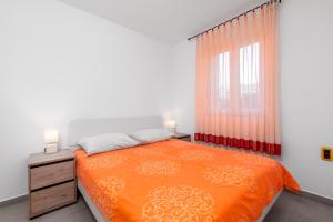 a bedroom with an orange bed and a window at Apartments Manuela in Pula