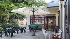 un patio con mesas, sillas y una sombrilla en Albergo Valentini, en Baceno