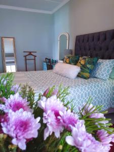 a bedroom with a bed with pink flowers in the foreground at Rest on 29 Rus in Oudtshoorn