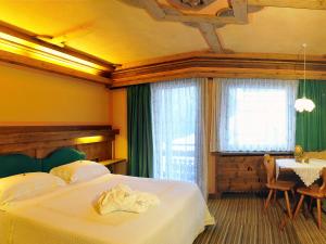a bedroom with a bed and a table and a window at Hotel Belvedere wellness in Falcade