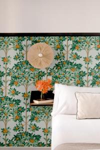 セビリアにあるTriana Boutique Apartments by Hommyhomeの緑とオレンジの花の壁紙を用いたベッドルーム1室