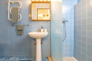 La salle de bains est pourvue d'un lavabo, d'un miroir et de carrelage bleu. dans l'établissement Red House 2- With terrace, à Porto