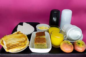 a tray of food with bread and apples and glasses of orange juice at Nuu Motel in São Paulo +34 photos