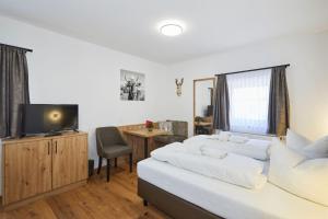 1 Schlafzimmer mit 2 Betten und einem Schreibtisch mit einem TV in der Unterkunft Gasthaus Ulrichshögl in Ainring