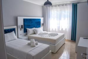 a white bedroom with two beds and a window at Gimi Apartments Shengjin in Shëngjin