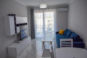 a living room with a blue couch and a tv at Gimi Apartments Shengjin in Shëngjin