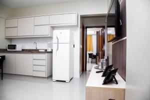 a kitchen with white cabinets and a white refrigerator at Executivo Flat 1 in Parauapebas