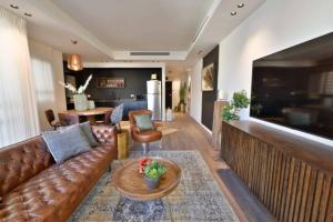 ein Wohnzimmer mit einem braunen Ledersofa und einem Tisch in der Unterkunft Heart of Tel Aviv, apartment 4 in Tel Aviv