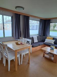 een woonkamer met een tafel en een bank bij Stacaravan 169 5* camping De kuilart in Friesland in Koudum