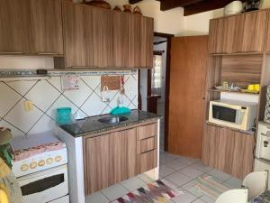 a small kitchen with a sink and a stove at Excelente casa na Praia do Coqueiro com 4 suítes a 100m da praia in Coqueiro
