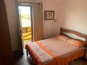 CoqueiroにあるExcelente casa na Praia do Coqueiro com 4 suítes a 100m da praiaのベッドルーム1室(ベッド1台付)、スライド式ガラスドアが備わります。