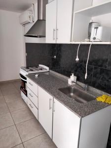 a white kitchen with a sink and a stove at Mendoza de sol in Villa Nueva