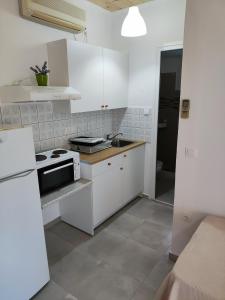 a kitchen with white cabinets and a sink and a stove at KOUVERTA APARTMENTS in Ermioni +14 photos