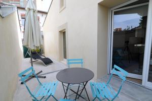 eine Terrasse mit einem Tisch, Stühlen und einem Sonnenschirm in der Unterkunft - Résidence Martimprey ! - in Nancy