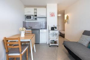 a small kitchen and living room with a table and a couch at Joli studio avec vue panoramique sur la Mer in Houlgate