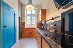 a kitchen with a blue door and a brick wall at Apartament Foto Loft - Villa Vinci - Z prywatnym monitorowanym parkingiem - Space Apart in Jelenia Góra