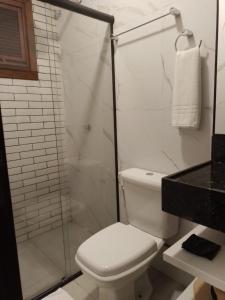 uma casa de banho com um WC e uma cabina de duche em vidro. em Terraço Flecheiras em Flecheiras