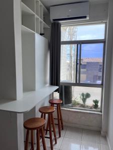 Apartamento em Amaralina في سلفادور: مطبخ مع كراسي و نافذة مطلة