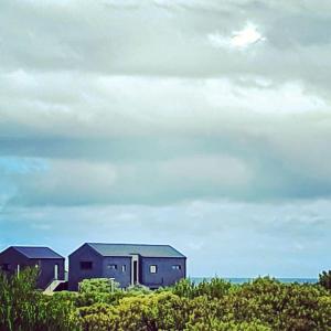Une rangée de maisons sur la plage sous un ciel nuageux dans l'établissement Southern most tip of Africa apartment with sea views, à Agulhas