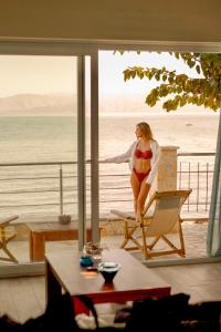 卡沃斯的住宿－Ekati Mare Boutique Resort，坐在靠近海洋的椅子上的比基尼女人