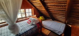 an attic bedroom with two beds and a window at Venha Juntos Guest Homes in Miramar