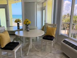 a dining room with a white table and chairs and windows at Beach Blessed - Sea View at Symphony Beach Club in Ormond Beach