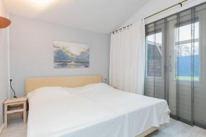 biała sypialnia z łóżkiem i oknem w obiekcie Eysingastate w mieście Rinsumageest