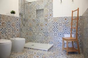 a bathroom with a toilet and a tiled wall at Sa Prazza GuestHouse in Cagliari