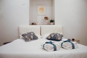 Una cama blanca con dos almohadas encima. en Sa Prazza GuestHouse, en Cagliari