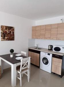 a kitchen with a table and a washing machine at Апартамент Quattro in Dobrich