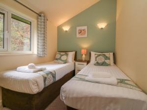 two twin beds in a room with a window at Chalet Log Cabin C9 in Ilfracombe