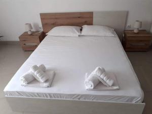 a large white bed with two white towels on it at Апартамент Quattro in Dobrich