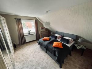 ein Schlafzimmer mit einem Bett mit orangefarbenen Kissen und einem Fenster in der Unterkunft Fewo Elke in Barsinghausen