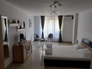 a bedroom with a bed and a television and a table at Апартамент Quattro in Dobrich