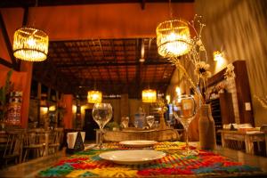 uma mesa com pratos, copos de vinho e luzes em Vivá Barra Hotel Pousada na Barra de São Miguel