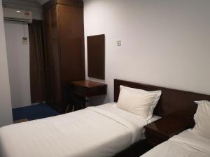 ein Hotelzimmer mit 2 Betten und einem Schreibtisch in der Unterkunft AeCOTEL in Sandakan