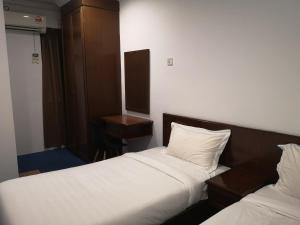 ein Hotelzimmer mit zwei Betten und einem Schreibtisch in der Unterkunft AeCOTEL in Sandakan