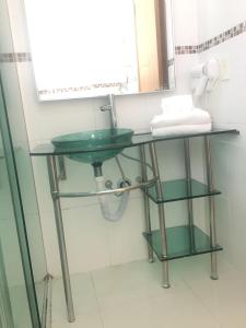 a bathroom with a green sink and a mirror at Emirates Hotel & Suites in Santana do Livramento
