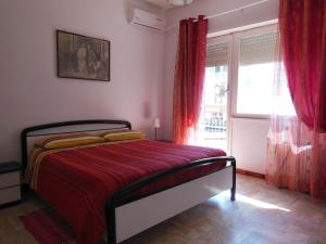 a bedroom with a bed with red curtains and a window at Casa Sista in Lido di Ostia