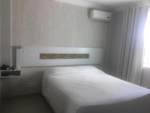 1 dormitorio con cama blanca y ventana en Emirates Hotel & Suites, en Santana do Livramento